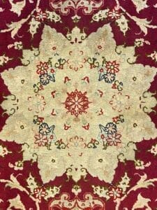 Particolare tappeto Tappeto Tabriz con motivi floreali su fondo rosso.