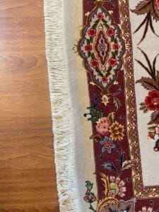 Un tappeto con disegni floreali su un pavimento di legno.