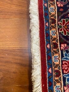 Primo piano di un tappeto rosso e blu su un pavimento in legno con bozza automatica.