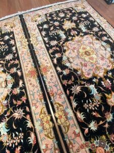 Un paio di tappeti neri e dorati su un pavimento di legno.