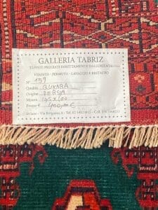 Un tappeto persiano rosso e verde con un'etichetta sopra.