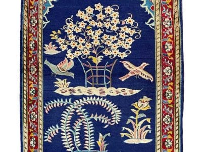 Un tappeto blu con uccelli e fiori sopra.