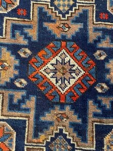 Un tappeto dal design geometrico caratterizzato dai toni del blu e dell'arancio.