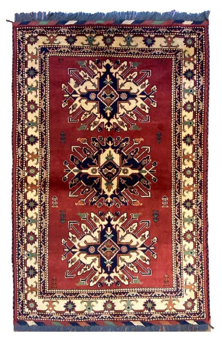 Tappeto tradizionale tessuto a mano con motivi geometrici simmetrici e un campo rosso predominante.