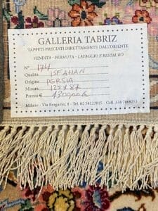 Etichetta del tappeto persiano, che di per sé fornisce informazioni insufficienti per il contesto o la rilevanza specifica del settore, mostrando l'origine, le dimensioni e il prezzo con i dettagli delle frange visibili.