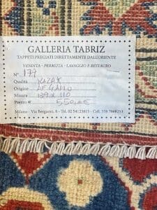 Etichetta su un tappeto kazak tessuto a mano che indica la vendita, la qualità, l'origine, la dimensione e le informazioni di contatto della galleria. Bozza automatica.
