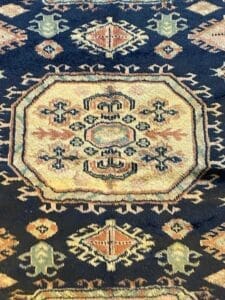 Primo piano di un tappeto a fantasia tradizionale con motivi geometrici e floreali, contrassegnato come "Bozza automatica".