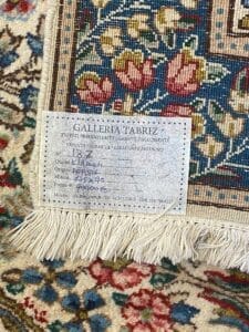 Un'etichetta della "galleria tabriz" attaccata a un tappeto persiano, che indica i dettagli sulla qualità, dimensione e origine del tappeto. Questa "Bozza automatica" fornisce spunti essenziali per