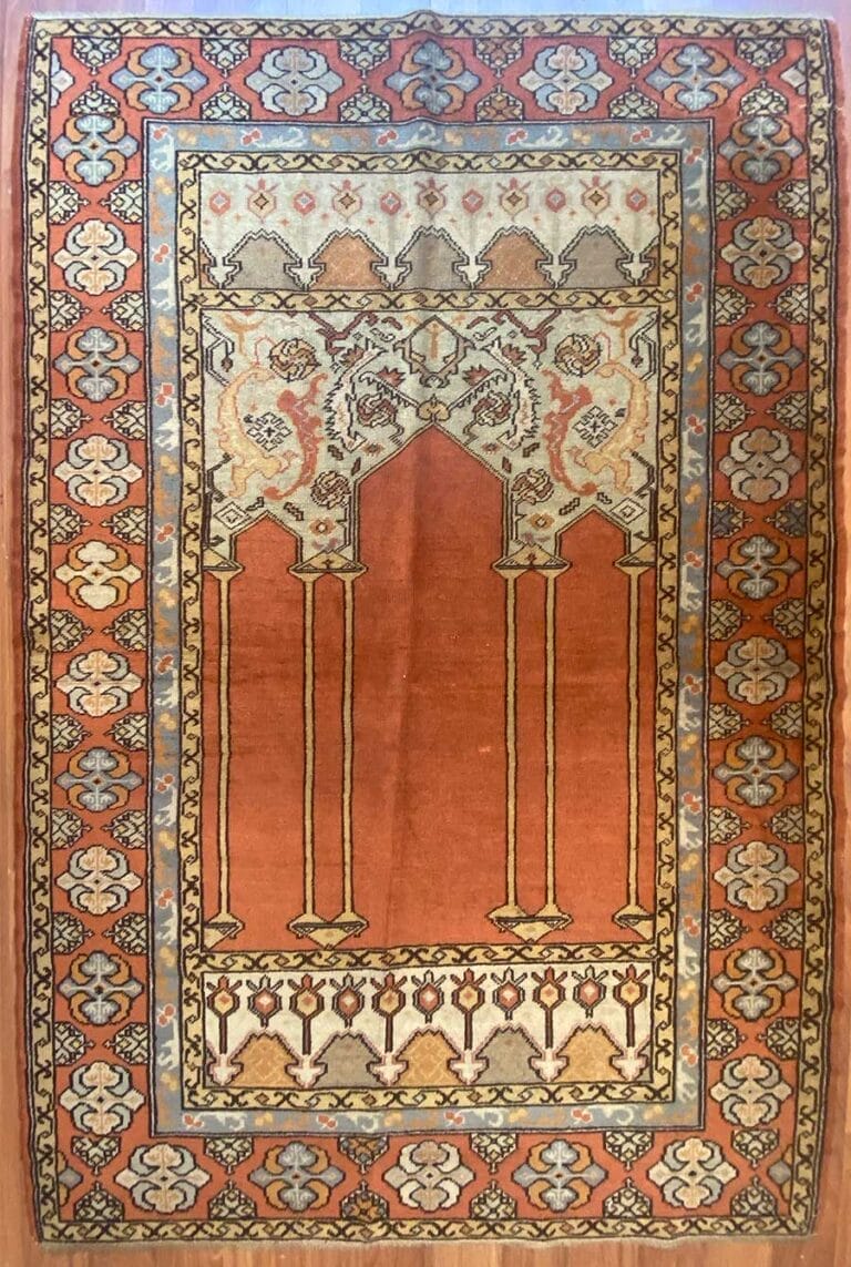Un tappeto tradizionale e decorato con un campo rosso centrale e una bozza automatica decorativa che mostra motivi intricati.