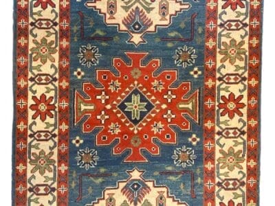 Tappeto tradizionale tessuto a mano con motivi geometrici simmetrici e disegno a medaglione centrale su sfondo blu.