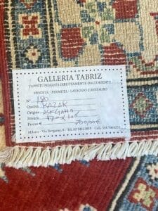 Un'etichetta della Galleria Tabriz su un tappeto a motivi geometrici, che riporta i dettagli del prodotto di un tappeto 