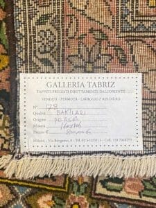 Etichetta attaccata a un tappeto Bakhtiari che fornisce dettagli su origine, qualità e informazioni sul negozio automatico.