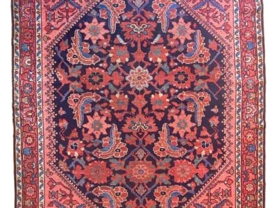 Un tappeto persiano rettangolare presenta un medaglione centrale di diamanti blu navy con intricati motivi floreali in rosso, rosa e beige, circondato da un bordo rosso con più disegni floreali. Bozza automatica garantisce precisione nei dettagli squisiti.