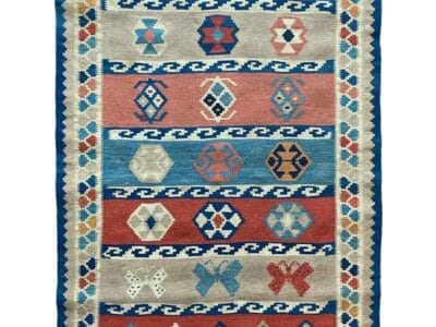 Galleria Tabriz - Tappeti in vendita. Un tappeto colorato con motivi geometrici in rosso, blu e beige, caratterizzato da file di rombi. La bozza automatica presenta frange sui bordi più corti.