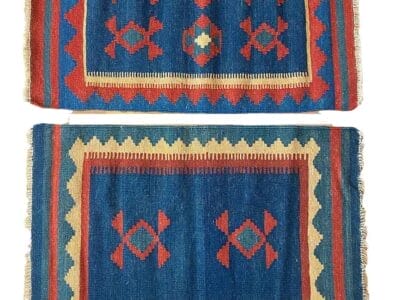 Galleria Tabriz - Tappeti in vendita. Due tappeti rettangolari tessuti con motivi geometrici nei colori rosso, blu, giallo e beige. Uno presenta tre forme di diamante centrali; l'altro ne ha quattro su sfondo blu e bordo rosso. Questi disegni appaiono meticolosamente realizzati, somiglianti a una bozza automatica.