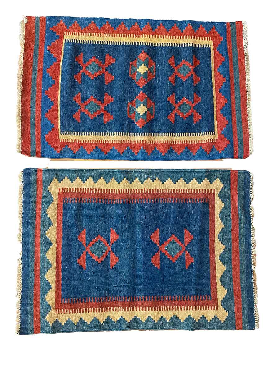 Galleria Tabriz - Tappeti in vendita. Due tappeti rettangolari tessuti con motivi geometrici nei colori rosso, blu, giallo e beige. Uno presenta tre forme di diamante centrali; l'altro ne ha quattro su sfondo blu e bordo rosso. Questi disegni appaiono meticolosamente realizzati, somiglianti a una bozza automatica.