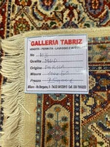 Galleria Tabriz - Tappeti in vendita. Primo piano di un'etichetta di un tappeto Tabriz che mostra l'origine in Persia. Il prezzo è elencato come 2.700 euro per questo capolavoro di bozza automatica, con dimensioni di 400x300 cm. Il tappeto vanta un design colorato e intricato.