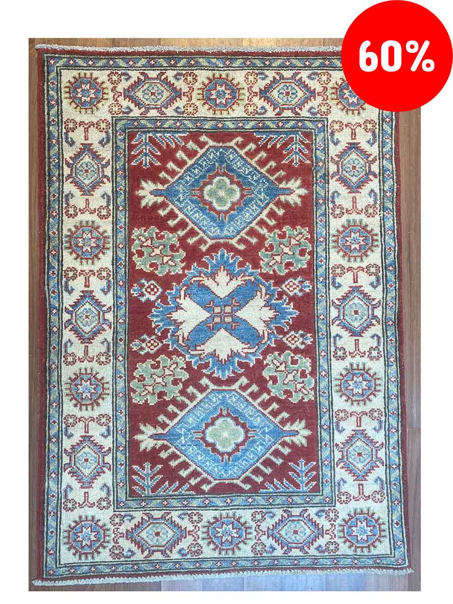 Galleria Tabriz - Tappeti in vendita. Un tappeto tradizionale con motivi rossi, blu e crema mette in mostra intricati disegni geometrici. Nell'angolo in alto a destra, un cerchio rosso mostra "60%" in grassetto bianco, una bozza automatica di stile ed eleganza.