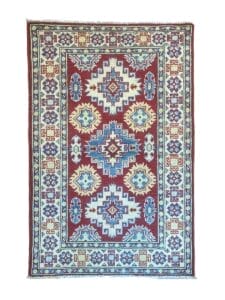 Galleria Tabriz - Tappeti in vendita. Un tappeto con motivo geometrico vibrante caratterizzato da disegni rossi, blu e bianchi. Vanta un motivo centrale a medaglione circondato da un bordo intricato, che ricorda la precisione e i dettagli di una bozza automatica.