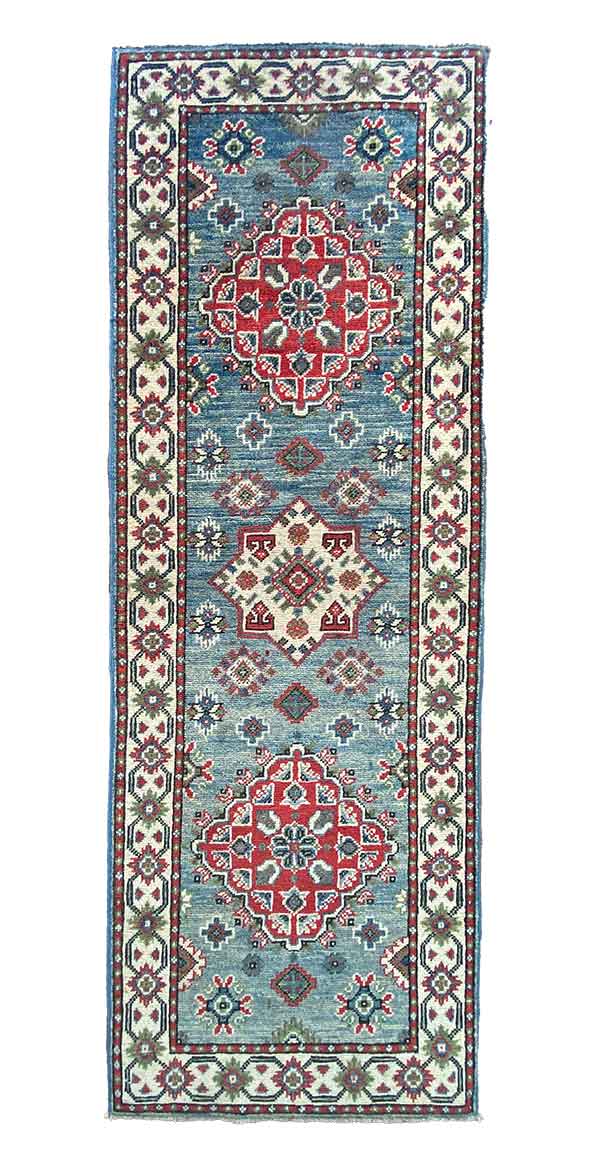 Galleria Tabriz - Tappeti in vendita. Questo tappeto rettangolare vanta un intricato motivo floreale e geometrico con una tavolozza di rosso, blu e crema. I motivi centrali a diamante sono circondati da disegni più piccoli e da un bordo decorativo, che mette in mostra una bozza automatica che fonde senza sforzo eleganza e maestria.
