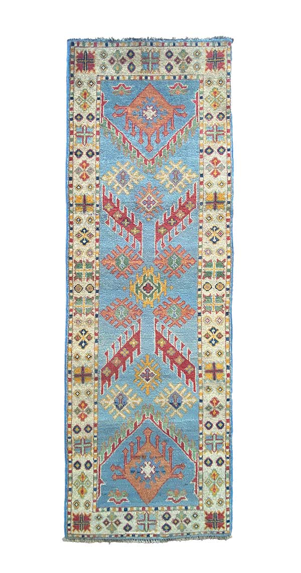 Galleria Tabriz - Tappeti in vendita. Un tappeto rettangolare con motivi geometrici blu e arancione, con intricati disegni sui bordi nei colori rosso, giallo e crema.