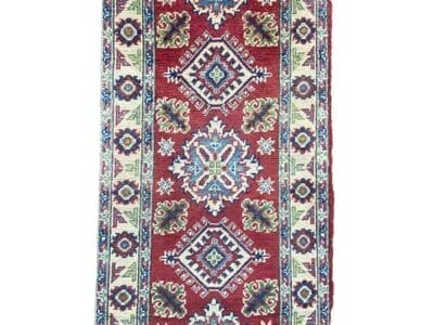 Galleria Tabriz - Tappeti in vendita. Un tappeto tradizionale lungo e rettangolare con sfondo rosso, caratterizzato da intricati motivi geometrici e floreali nei toni del blu, del verde e del bianco.