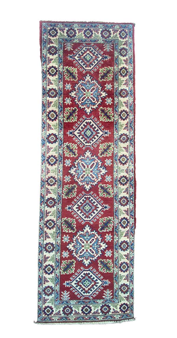 Galleria Tabriz - Tappeti in vendita. Un tappeto tradizionale lungo e rettangolare con sfondo rosso, caratterizzato da intricati motivi geometrici e floreali nei toni del blu, del verde e del bianco.