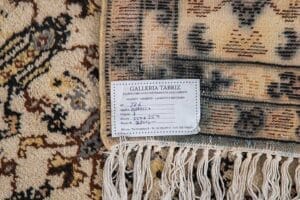 Galleria Tabriz - Tappeti in vendita. Primo piano di un angolo di tappeto con etichetta Galleria Tabriz con dettagli scritti a mano, bordi sfrangiati e marchio automatico Bozza visibile.