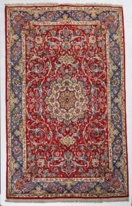 Galleria Tabriz - Tappeti in vendita. Tappeto persiano rosso con intricati motivi floreali, un medaglione centrale e bordi decorativi blu e oro: uno squisito Tappeto Isfahan che esemplifica la classica maestria di Tappeto Persia.
