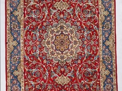 Galleria Tabriz - Tappeti in vendita. Tappeto persiano rosso con intricati motivi floreali, un medaglione centrale e bordi decorativi blu e oro: uno squisito Tappeto Isfahan che esemplifica la classica maestria di Tappeto Persia.