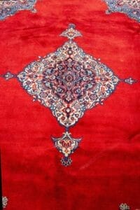 Galleria Tabriz - Tappeti in vendita. Tappeto rosso con medaglione centrale ornato e simmetrico con motivi blu, bianchi e rosso scuro, che ricorda un classico Tappeto Saruk della Persia.