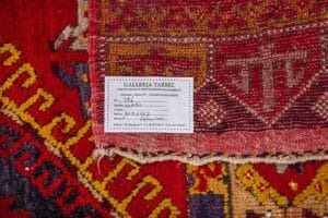 Galleria Tabriz - Tappeti in vendita. Un primo piano di un tappeto Passatoia Azari mostra un'etichetta della Galleria Tabriz che ne illustra i dettagli, evidenziando la lavorazione artigianale ispirata alla Persia.