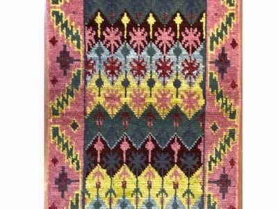 Un colorato tappeto kilim turco su un pavimento di legno.